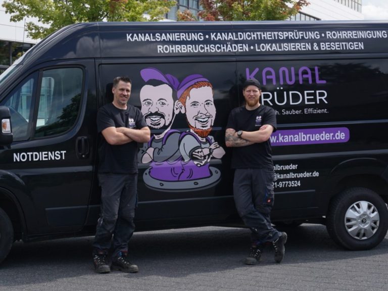 Ein Arbeiter führt eine Kamerainspektion an einem offenen Schacht in einer Wiese aus.