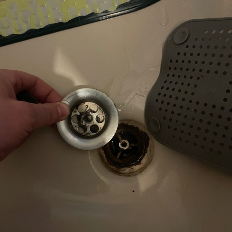 Gerüche lokalisieren Eine Hand zeigt ein loses Abfluss-Ventil einer Dusche.